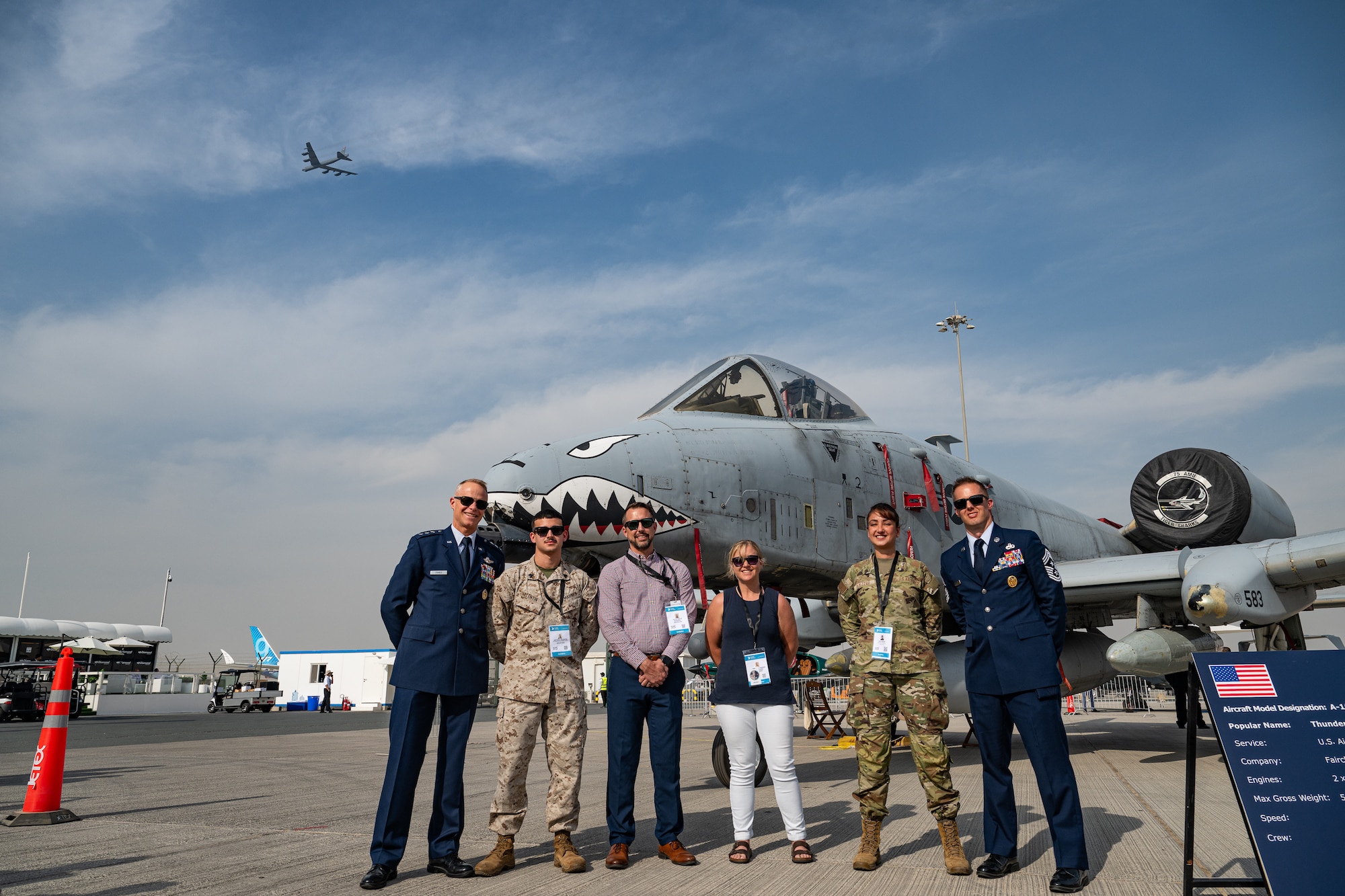 U.S. Air Force Lt. Gen. Derek France, Air Forces Central commander, stands with service members and Department of War civilians in front of an A-10 Thunderbolt aircraft while a B-52 Stratofortress aircraft flies in the background at the Al Maktoum International Airport, Dubai, Nov. 17, 2025. They attended the Dubai International Airshow, an event that strengthens ties between U.S. forces and international partners in aviation and national defense. (U.S. Air Force photo by Tech. Sgt. Justin Norton)