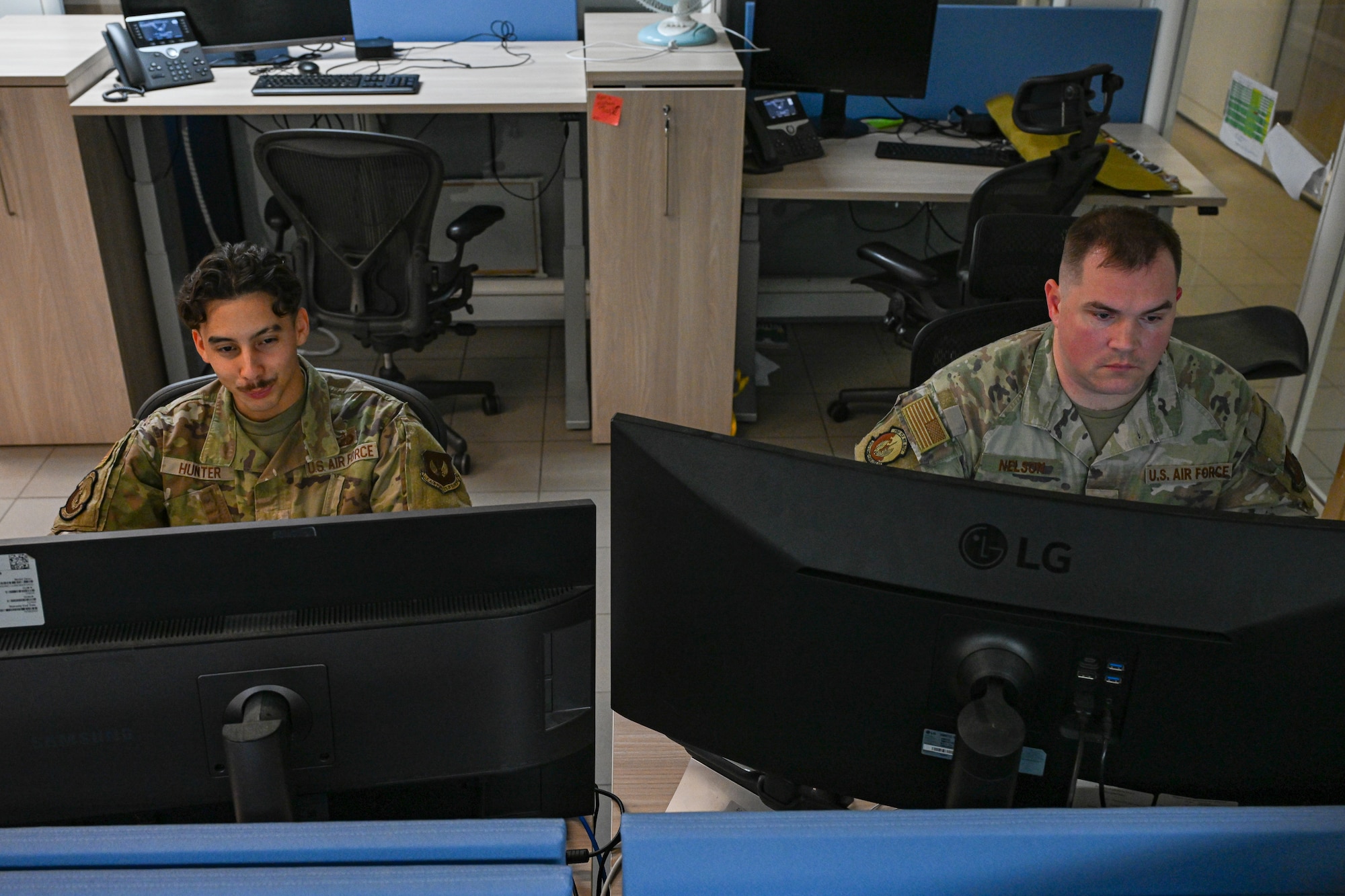 Airmen look at computers.