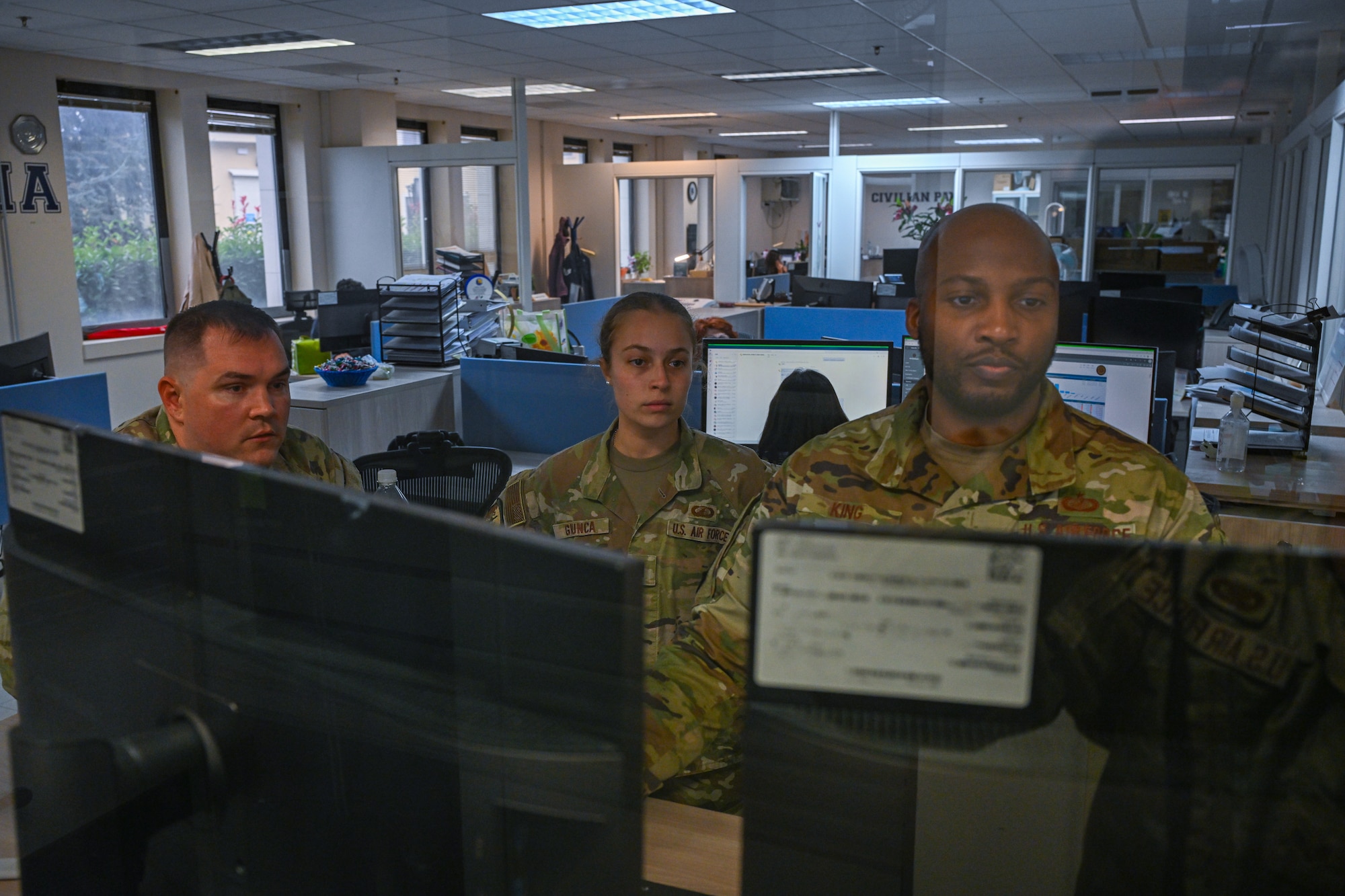Airmen look at a computer.