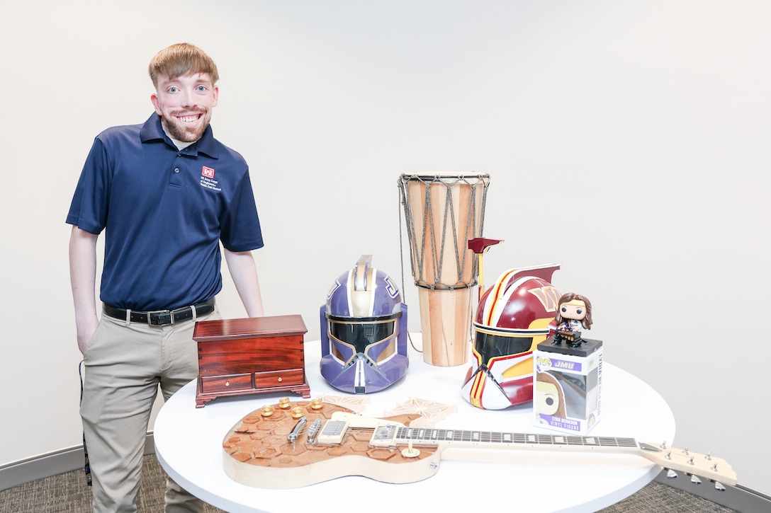 Man stands next to a table with different objects he made.