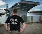 NCIS Special Agent in the foreground looking at USS Harry S. Truman (CVN-75)