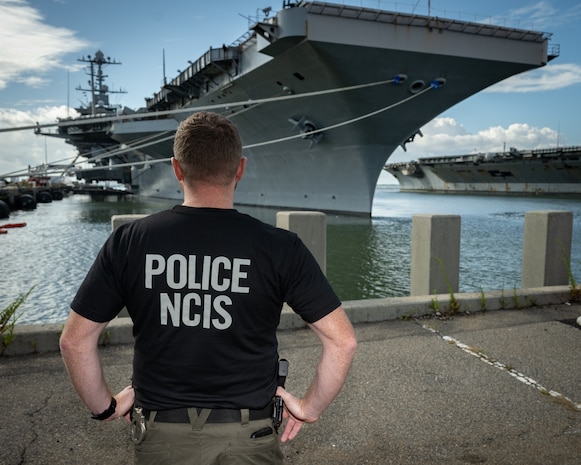 NCIS Special Agent in the foreground looking at USS Harry S. Truman (CVN-75)