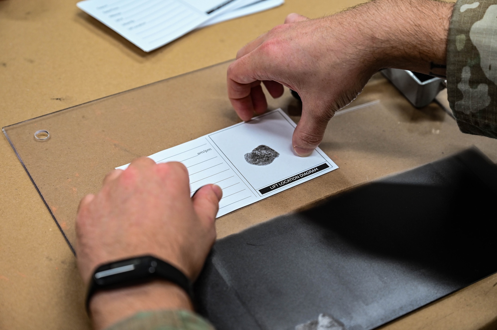 A man's hands hold a card with a single fingerprint