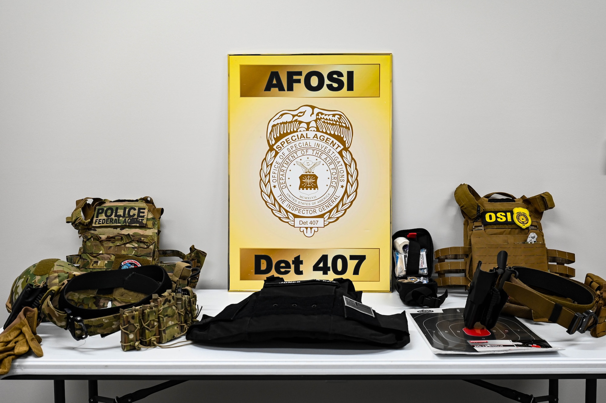 A yellow sign for AFOSI Detachment 407 sits on a table with body armor and weapon belts.