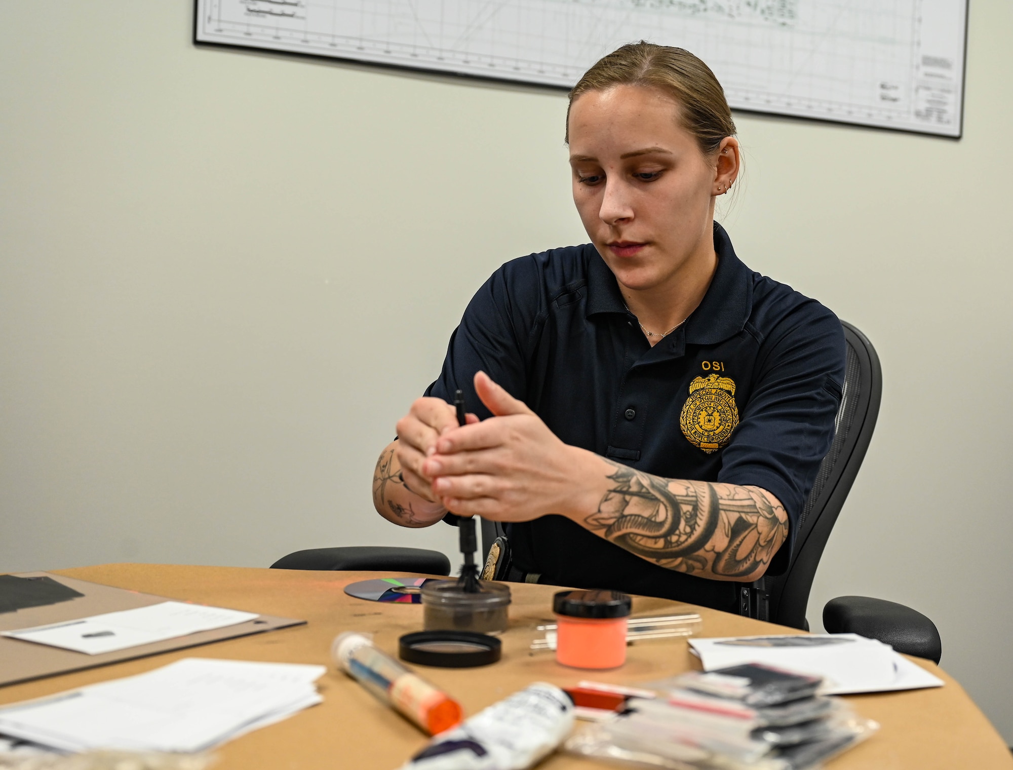 A woman in a dark blue OSI polo holds a fingerprint brush