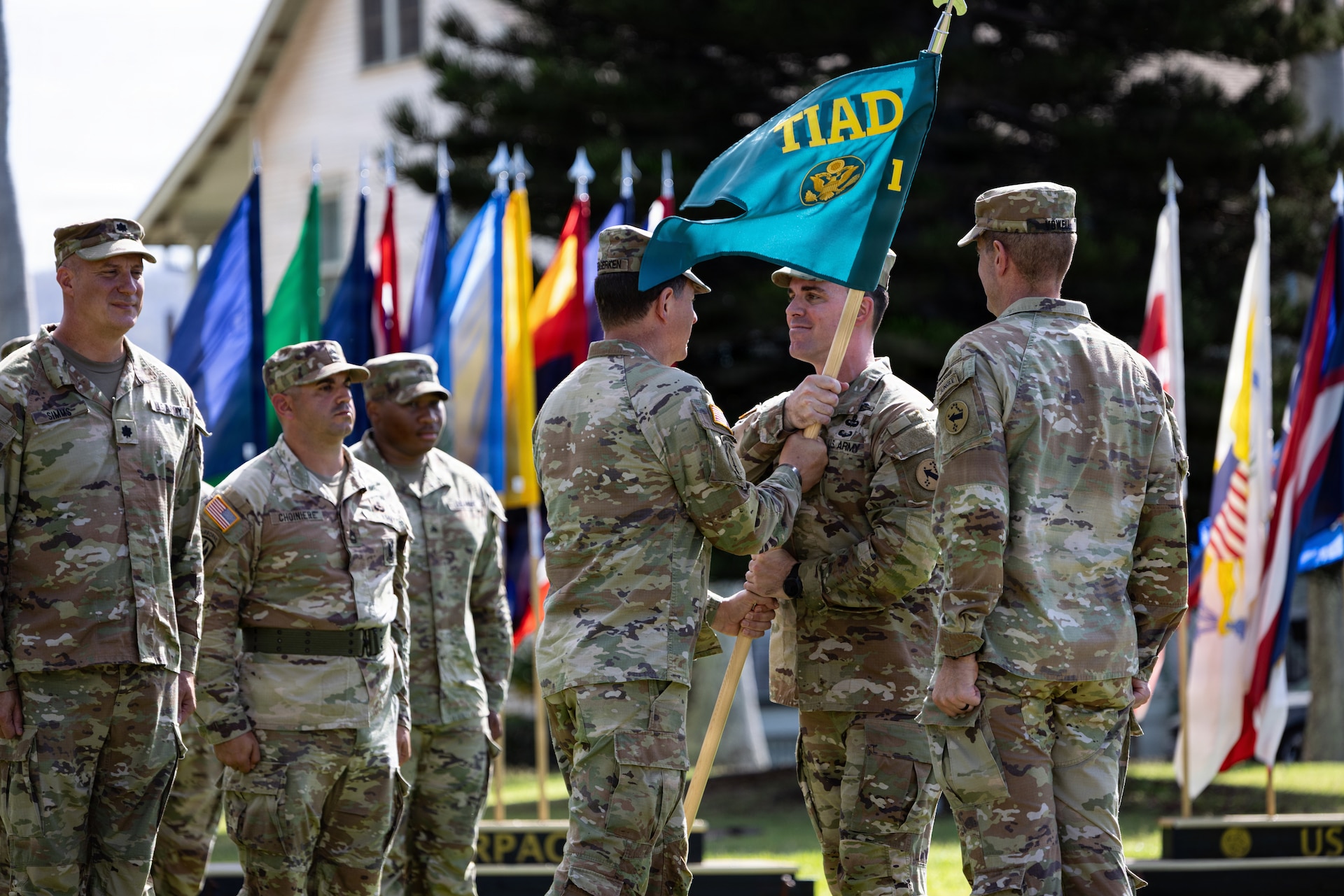 Col. Sean Heidgerken, commander of the 1st Theater Information Advantage Detachment, passes the newly uncased unit guidon to Command Sgt. Maj. Avery Bennett, the senior enlisted advisor, during the unit’s activation November 7, 2025, at Fort Shafter, Hawaii.
