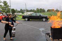 A woman uses a water extinguisher to put out a fire.