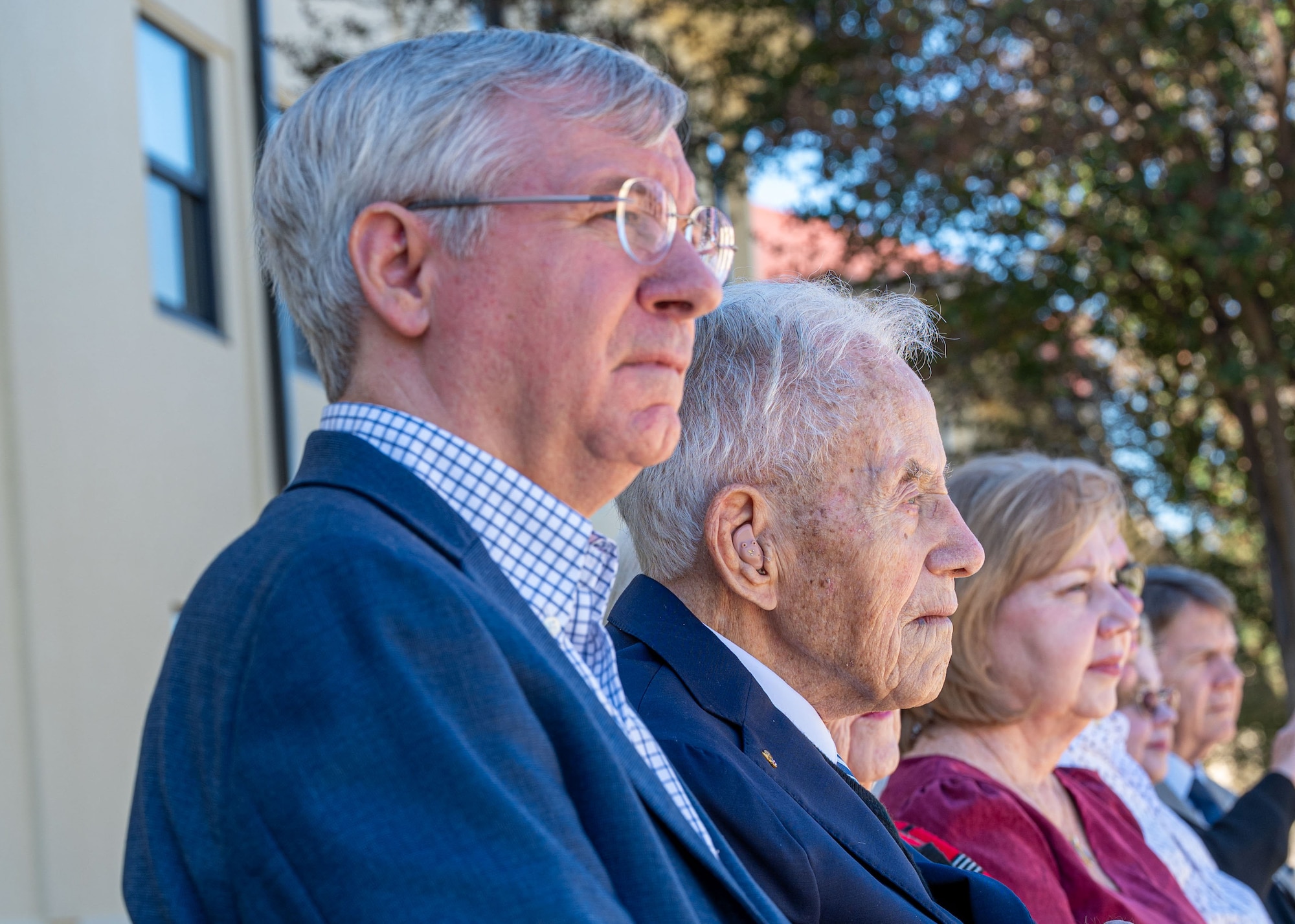 Robert E. Moriarty, left, Headquarters Air Force Deputy Assistant Secretary of the Air Force for Installations, watches a ceremony alongside retired U.S. Air Force Chief Warrant Officer 4 Robert Brow, center, and family members, during a guidon dedication ceremony at Maxwell Air Force Base, Alabama, Nov. 5, 2025.