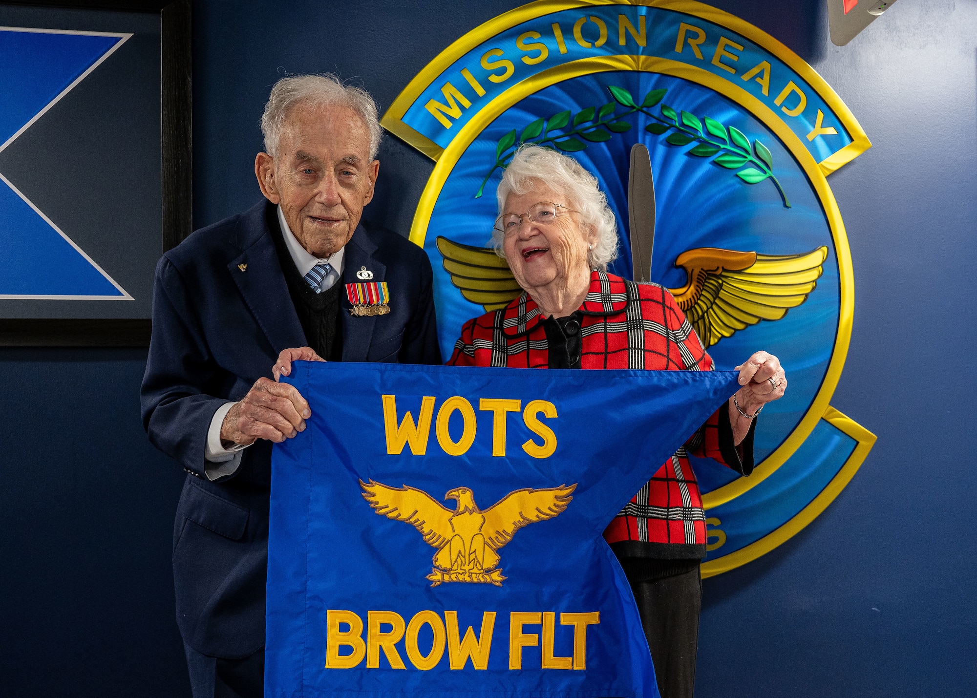 Retired U.S. Air Force Chief Warrant Officer 4 Robert Brow, and his wife Karen Brow, hold the newly presented Brow Flight pennant at Maxwell Air Force Base, Alabama, Nov. 5, 2025.