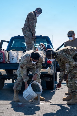 A photo of Airmen pouring concrete, smoothing concrete and observing the filling of a hole on an airfield.