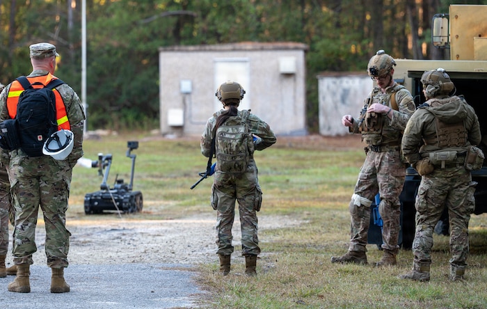 A photo of  Airmen standing in front of a robot with a camera.