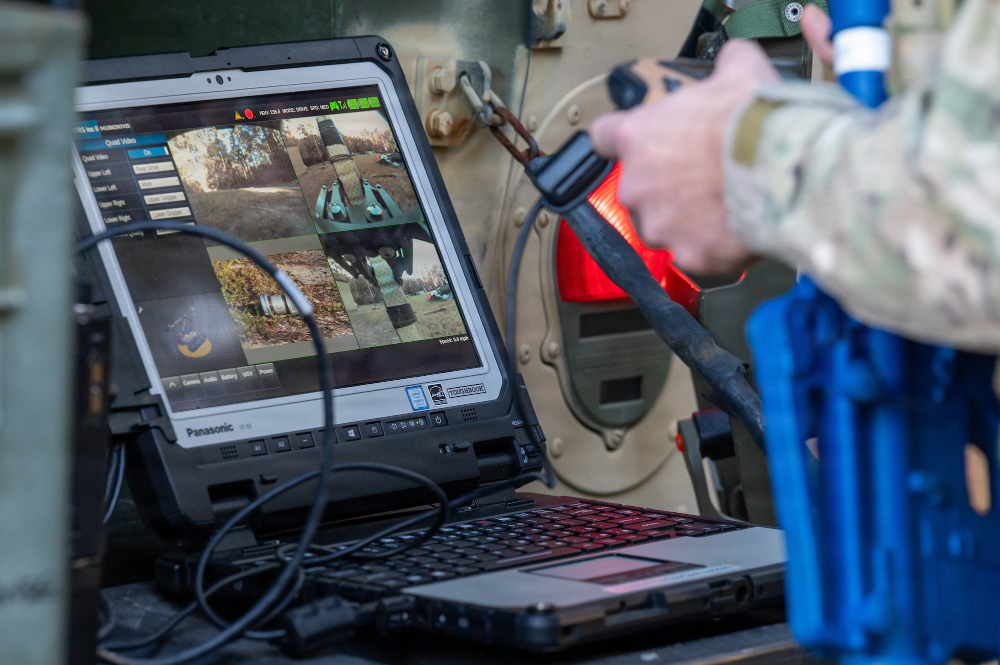 A photo of hands holding a controller in front of a computer with multiple cameras.