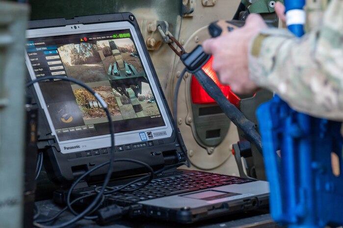 A photo of hands holding a controller in front of a computer with multiple cameras.