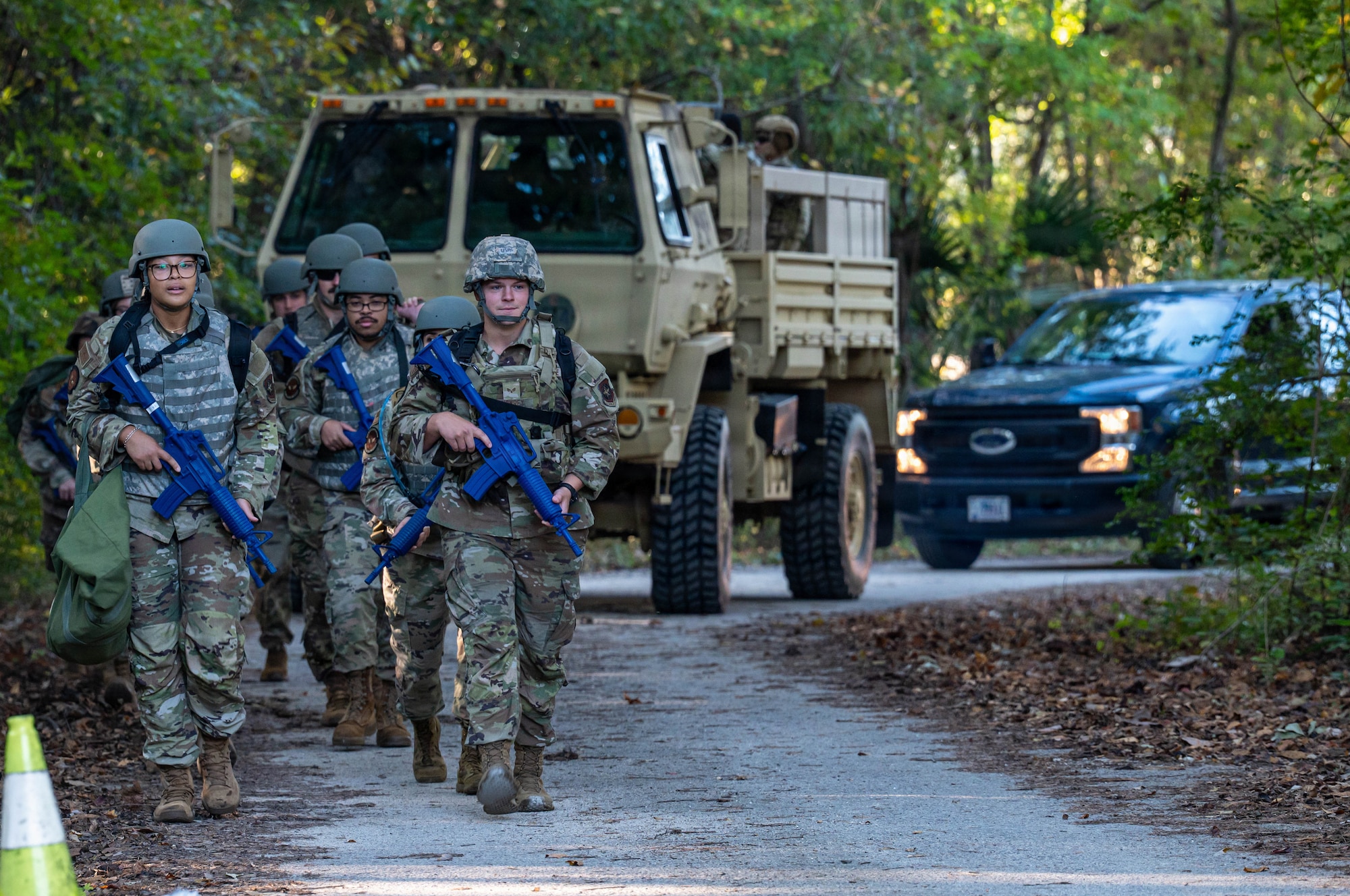 A photo of Airmen walking in formation, followed by vehicles.