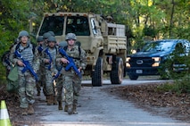 A photo of Airmen walking in formation, followed by vehicles.