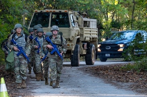 A photo of Airmen walking in formation, followed by vehicles.