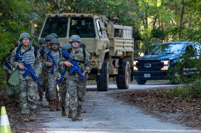 A photo of Airmen walking in formation, followed by vehicles.
