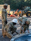 A photo of Airmen building the metal frame of a tent while crouched on the ground