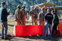 A photo of Airmen standing behind a barricade.