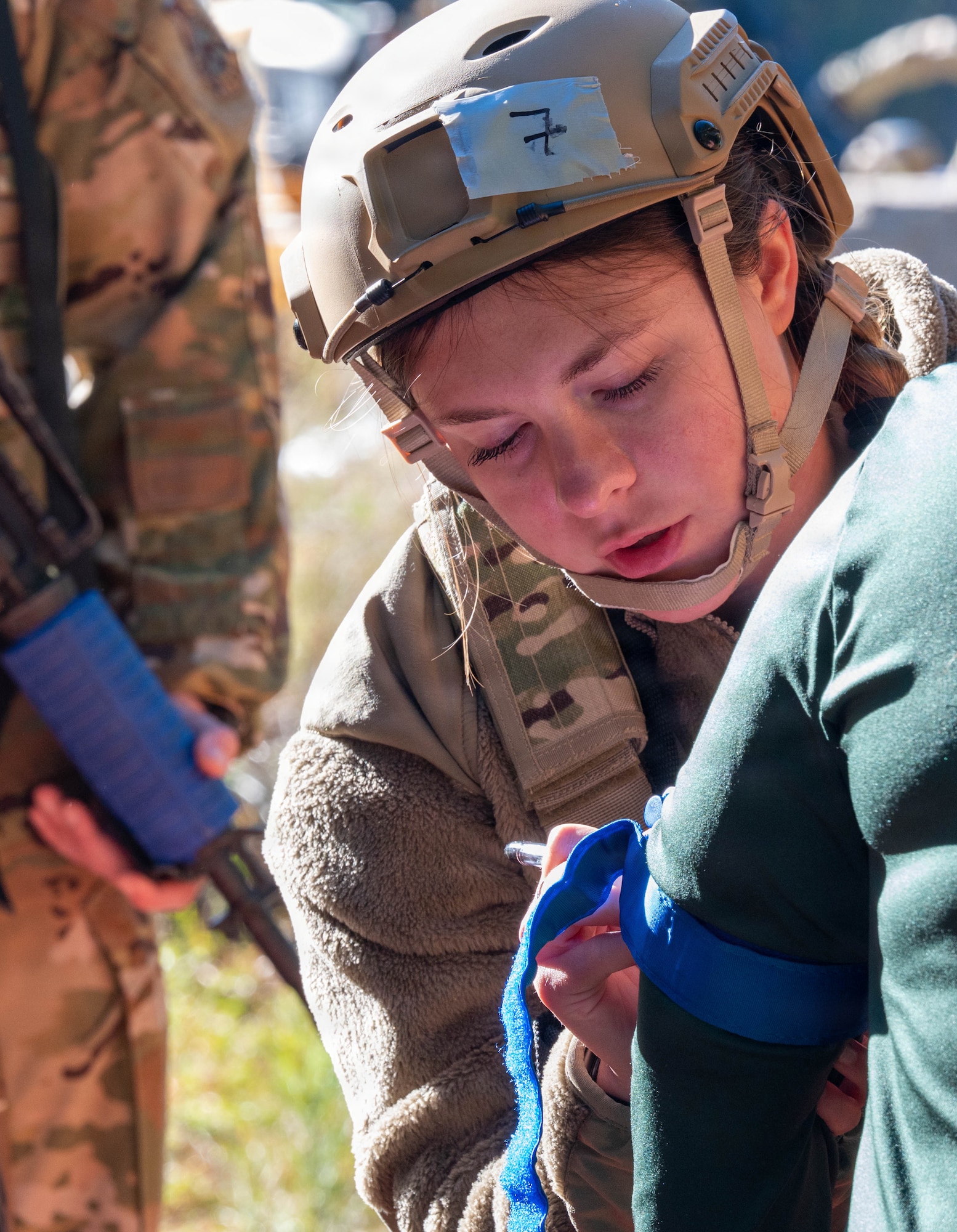 A photo of a female Airman writing on the arm of a patient