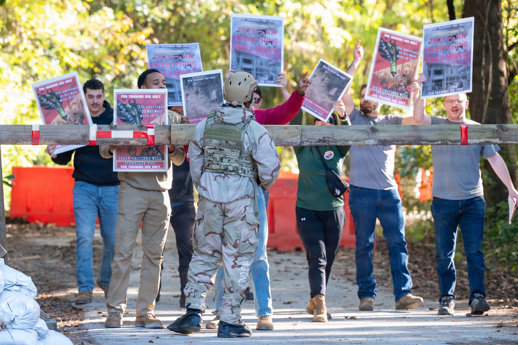A photo of Airmen holding signs behind a barricade during a protest simulation