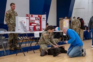 A participant observes and discusses a simulated injured dog during the 2025 Health & Wellness Expo at Misawa Air Base, Japan, Nov. 14, 2025. The event fostered collaboration and connection by bringing members together to learn through hands-on demonstrations. (U.S. Air Force photo by Senior Airman Brittany Russell)