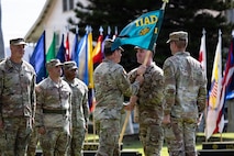 Col. Sean Heidgerken, commander of the 1st Theater Information Advantage Detachment, passes the newly uncased unit guidon to Command Sgt. Maj. Avery Bennett, the senior enlisted advisor, during the unit’s activation November 7, 2025, at Fort Shafter, Hawaii.