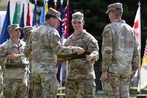Col. Sean Heidgerken and Command Sgt. Maj. Avery Bennett, the 1st Theater Information Advantage Detachment command team, uncase the unit guidon as part of the unit’s activation ceremony November 7, 2025, at Fort Shafter, Hawaii.
