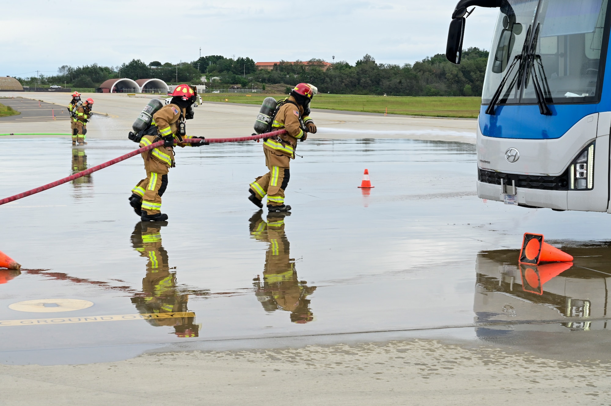 Two firefighters pull a hose.