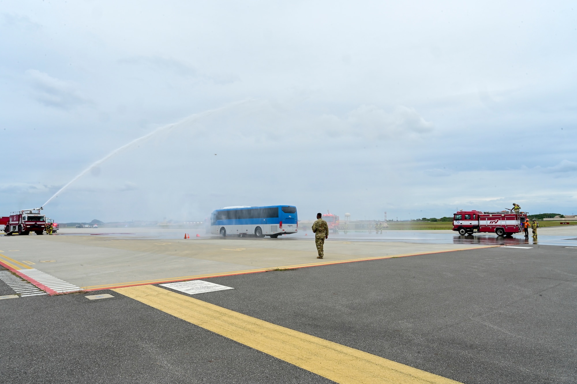 A man walks between firetrucks.