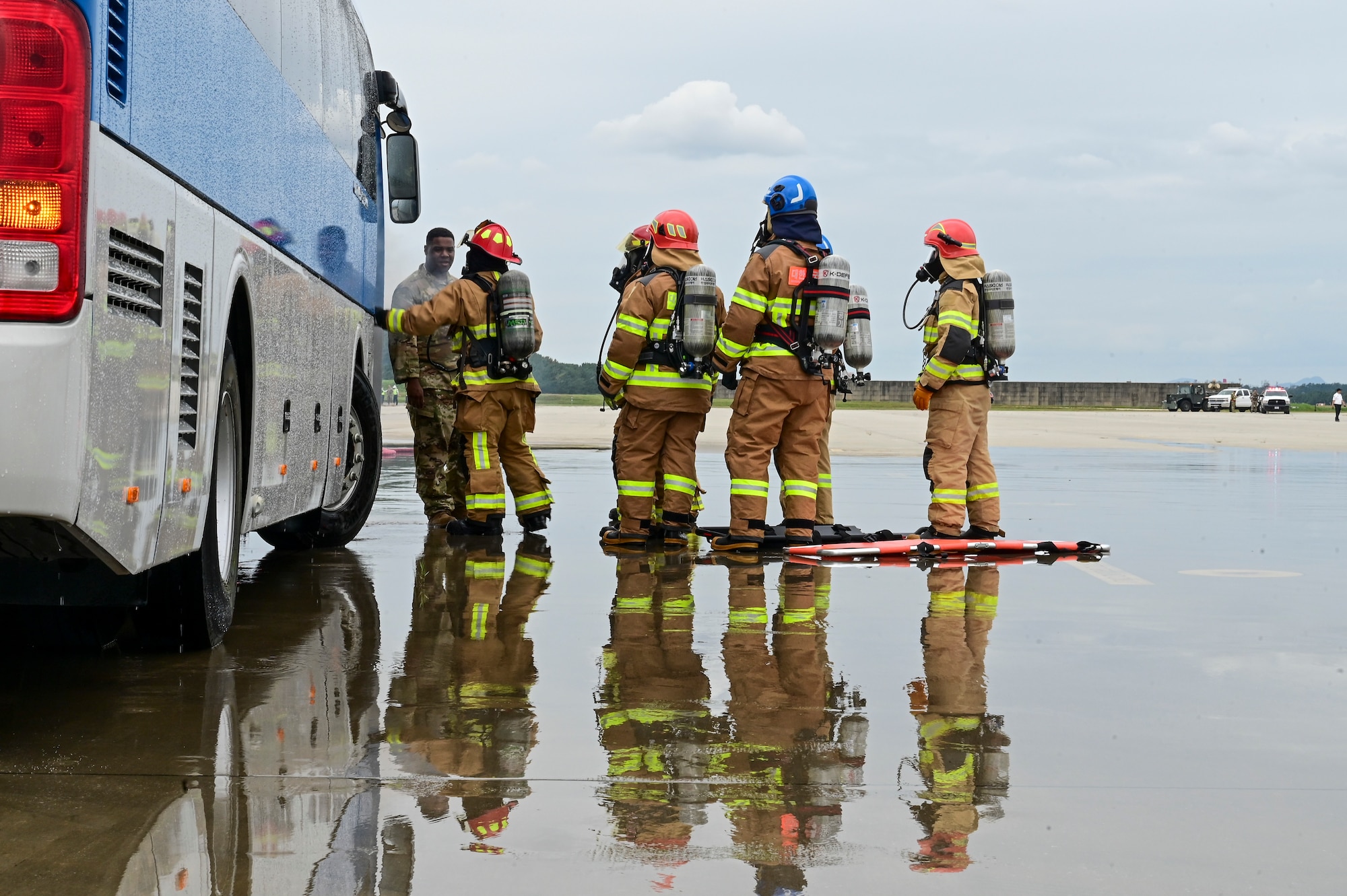 A group of firefighters stand beside a bus.