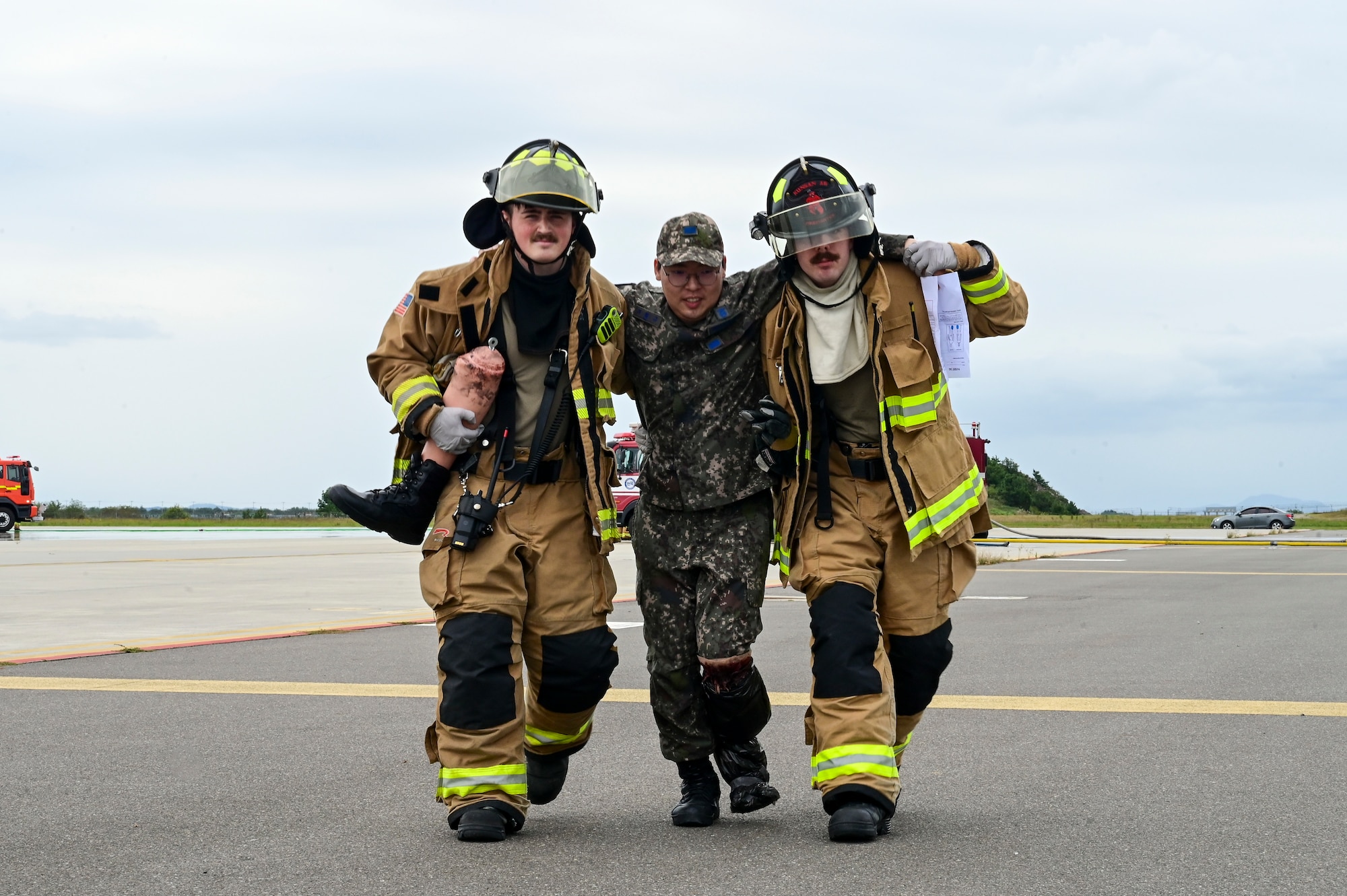 Two men help another walk.