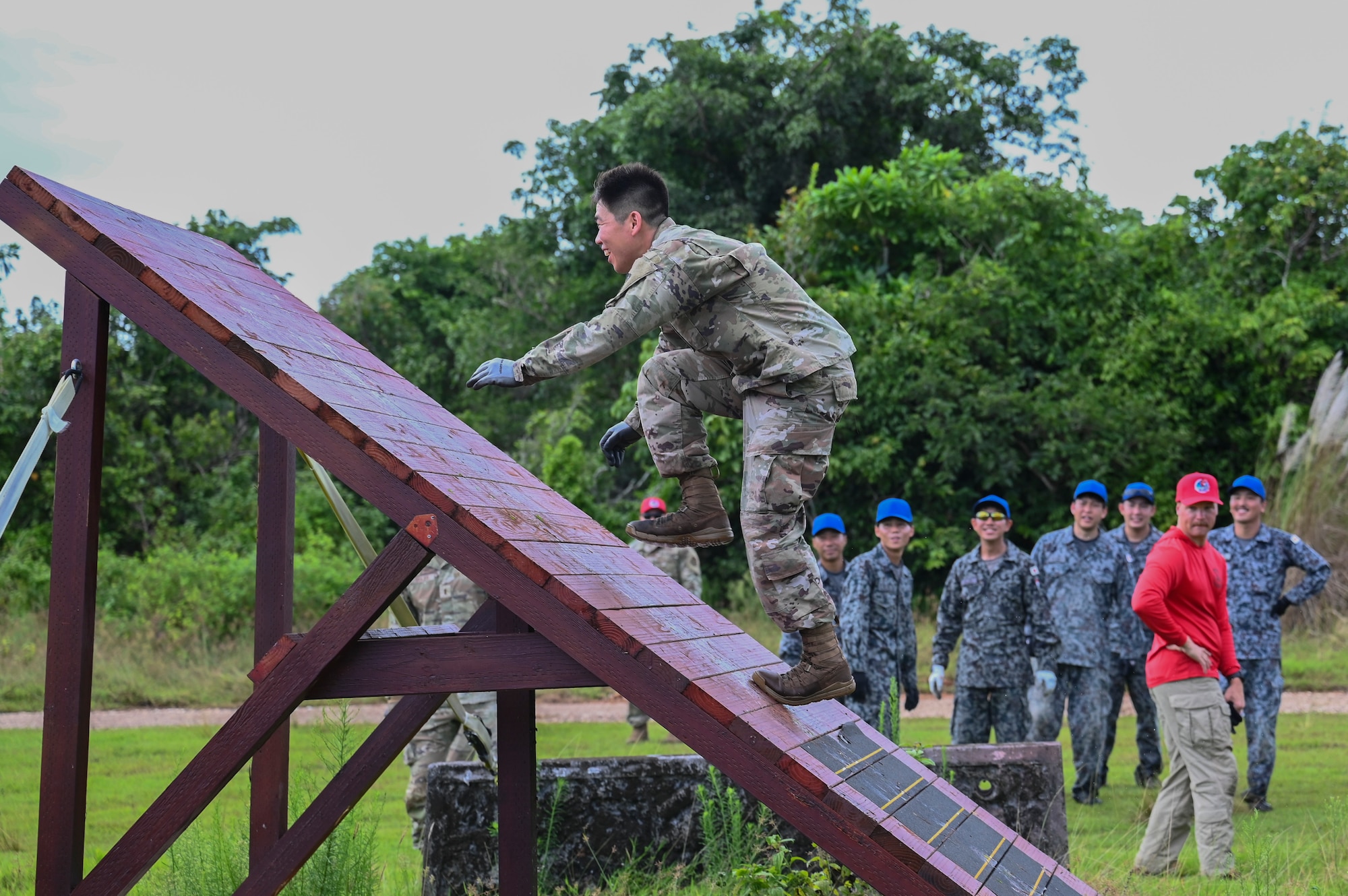 A U.S. Air Force Lt. climbs up a platform during an obstacle course for PERC while the other participants watch.