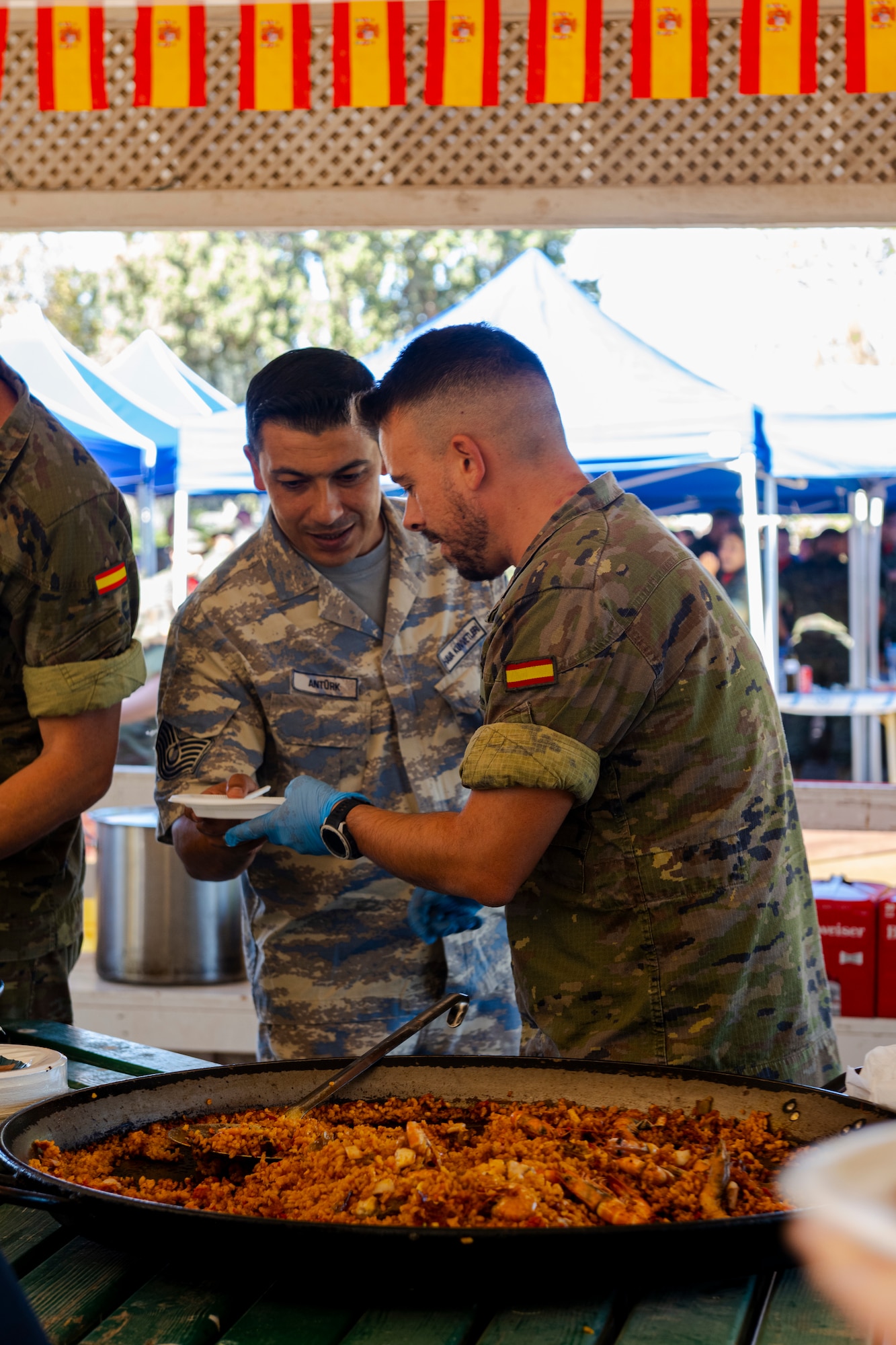 A Spanish Army service member gives food to a Turkish Air Force member