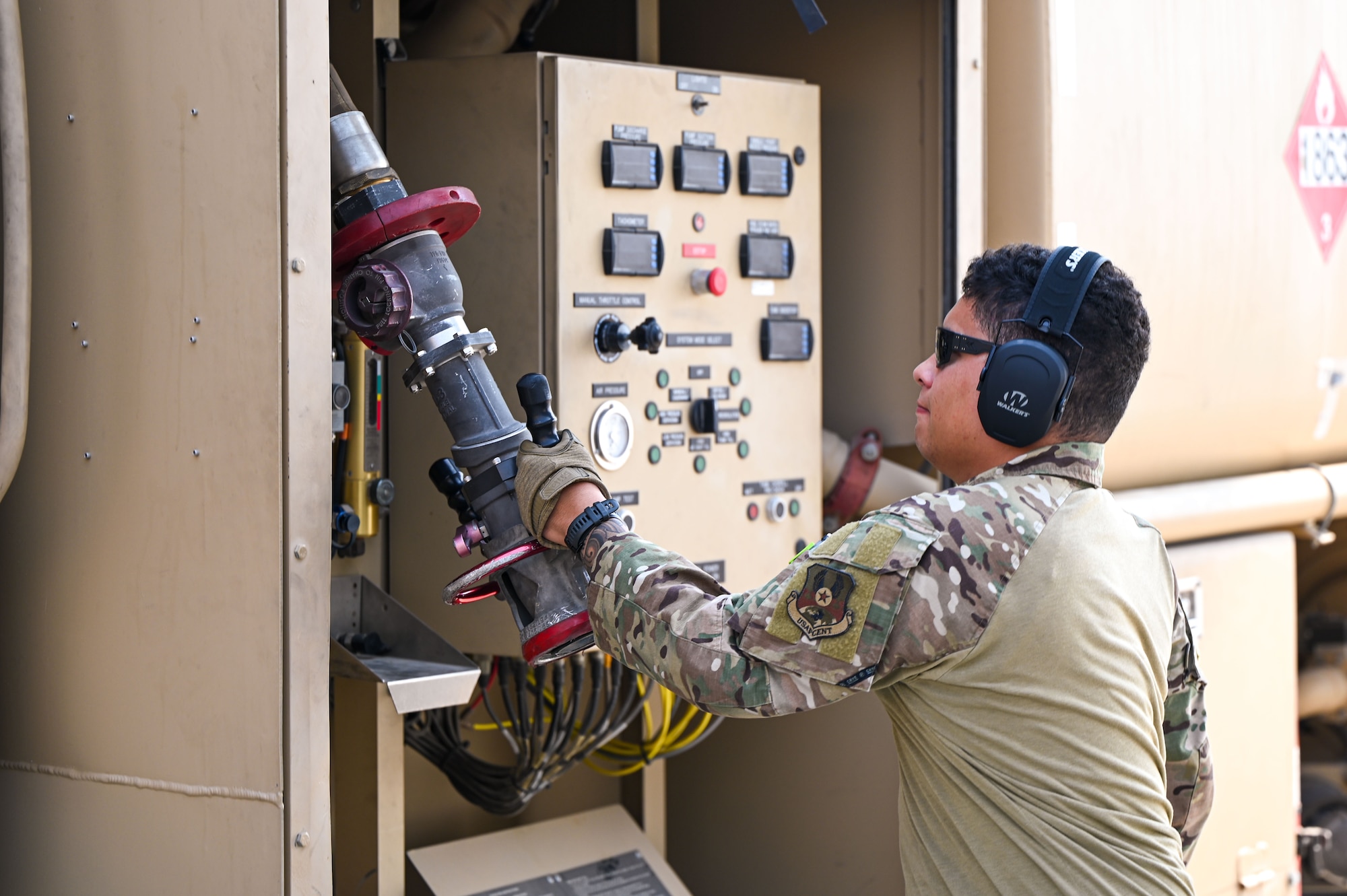 An Airman pulls a fuel hose from an R-11 Refueler truck