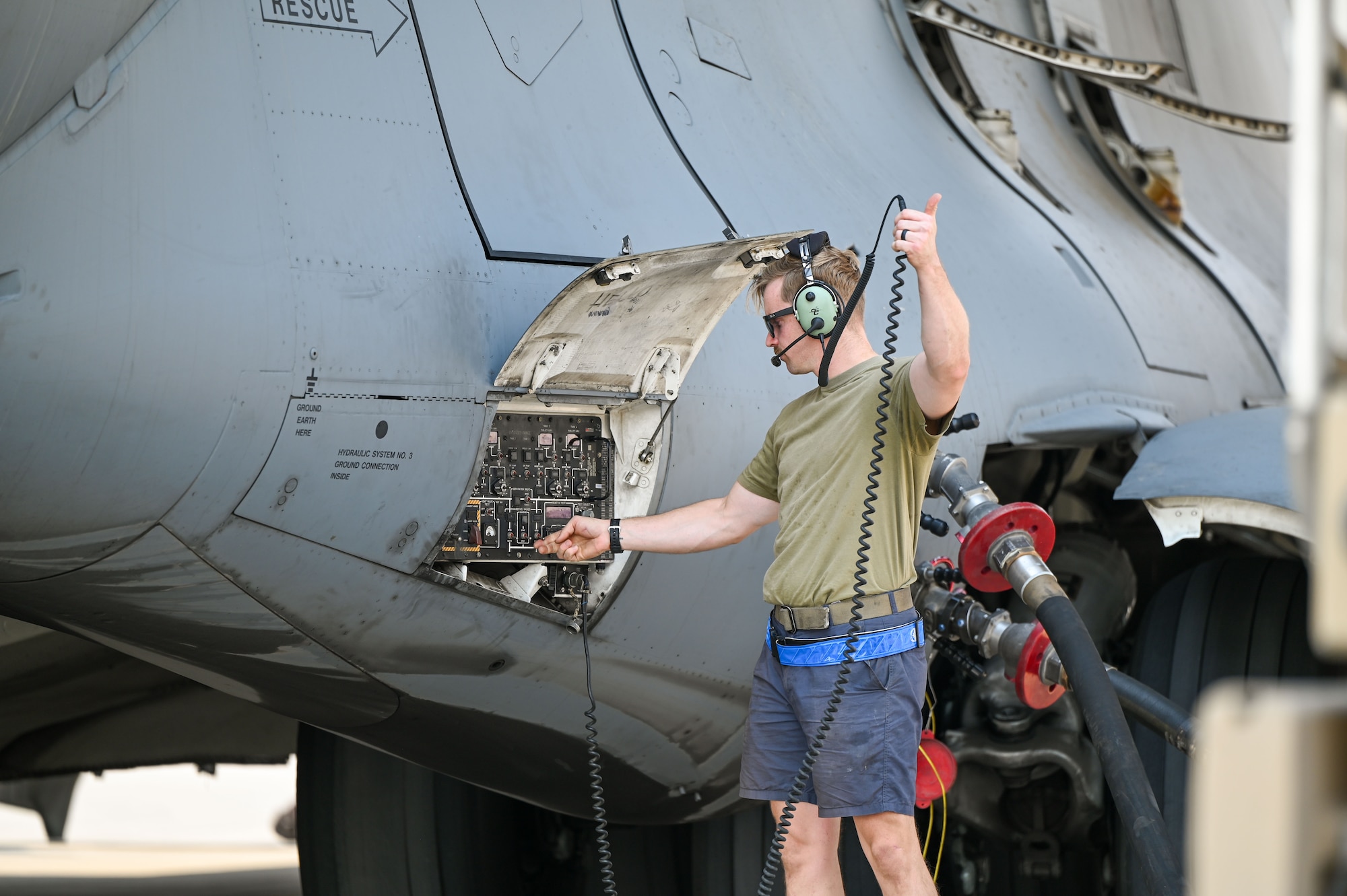 An Airman standing next to an aircraft gives a thumbs up