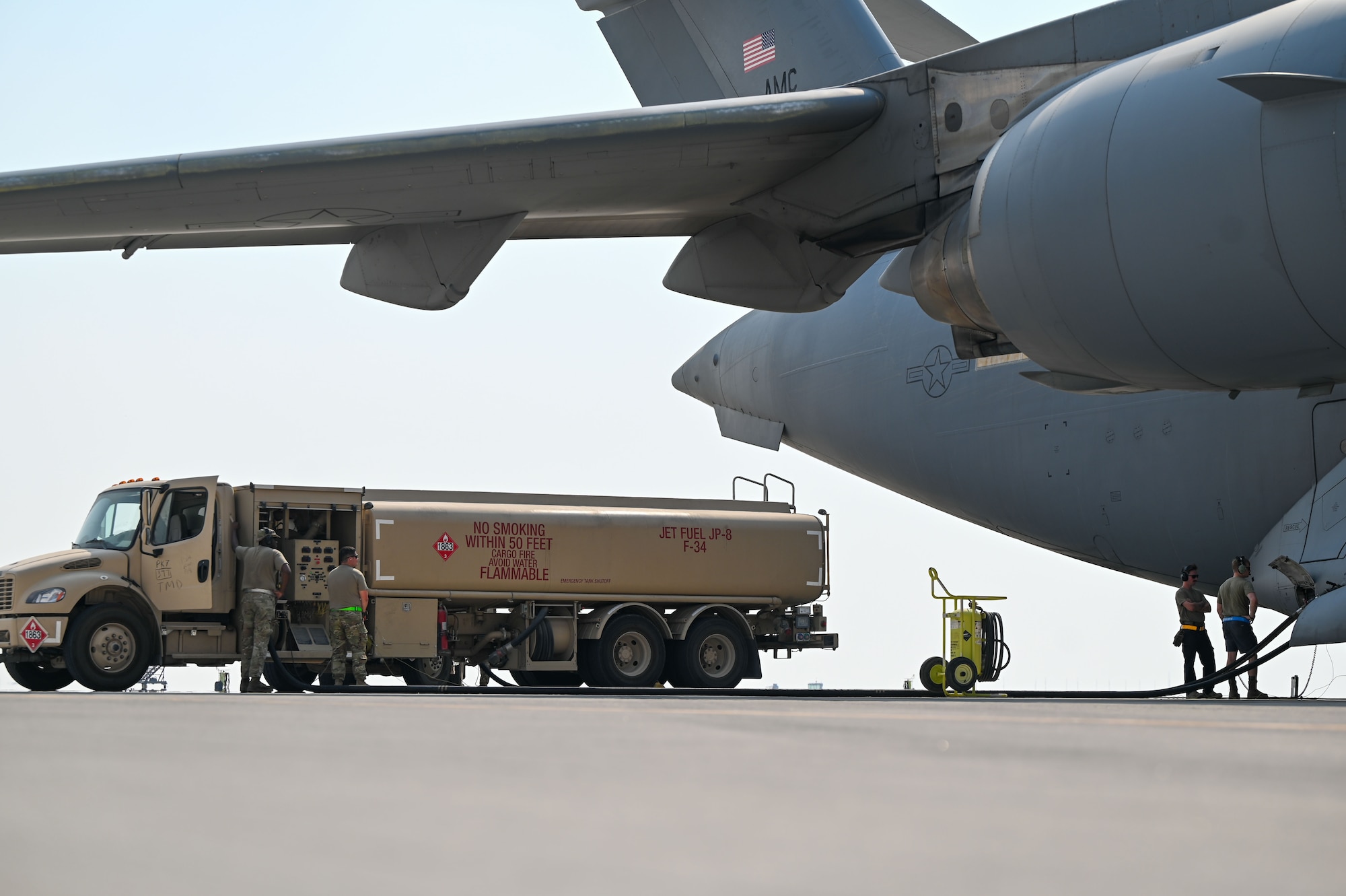 An R-11 Refueler truck is parked and connected to a C-17 aircraft