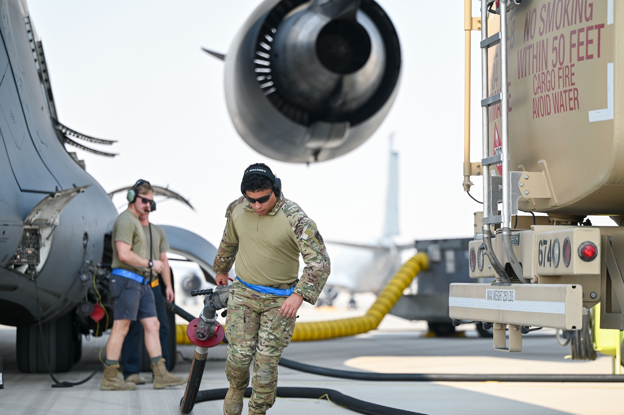 An Airman drags a fuel hose away from a C-17 Globemaster aircraft