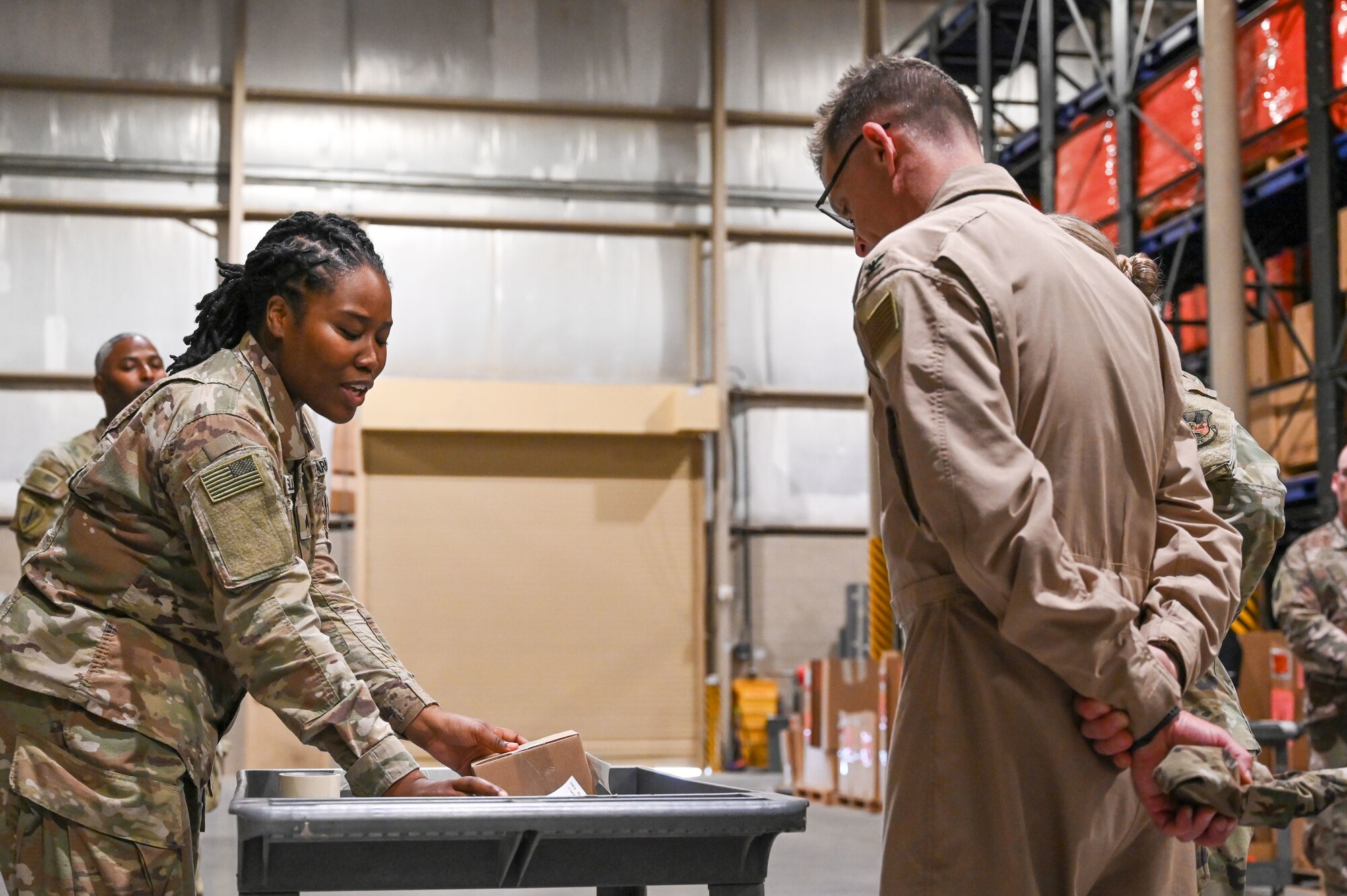 A Soldier holds two boxes up from a cart to show Col Lyons