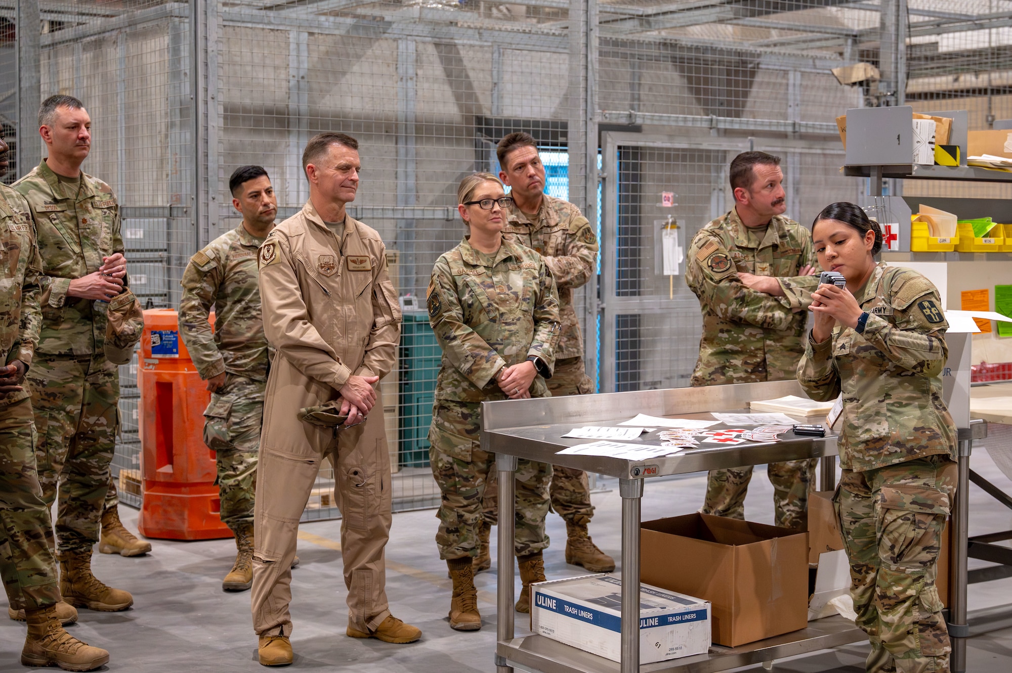 A Soldier in the right of the frame holds and points at a small thermometer while 6 Air Force officers stand and listen