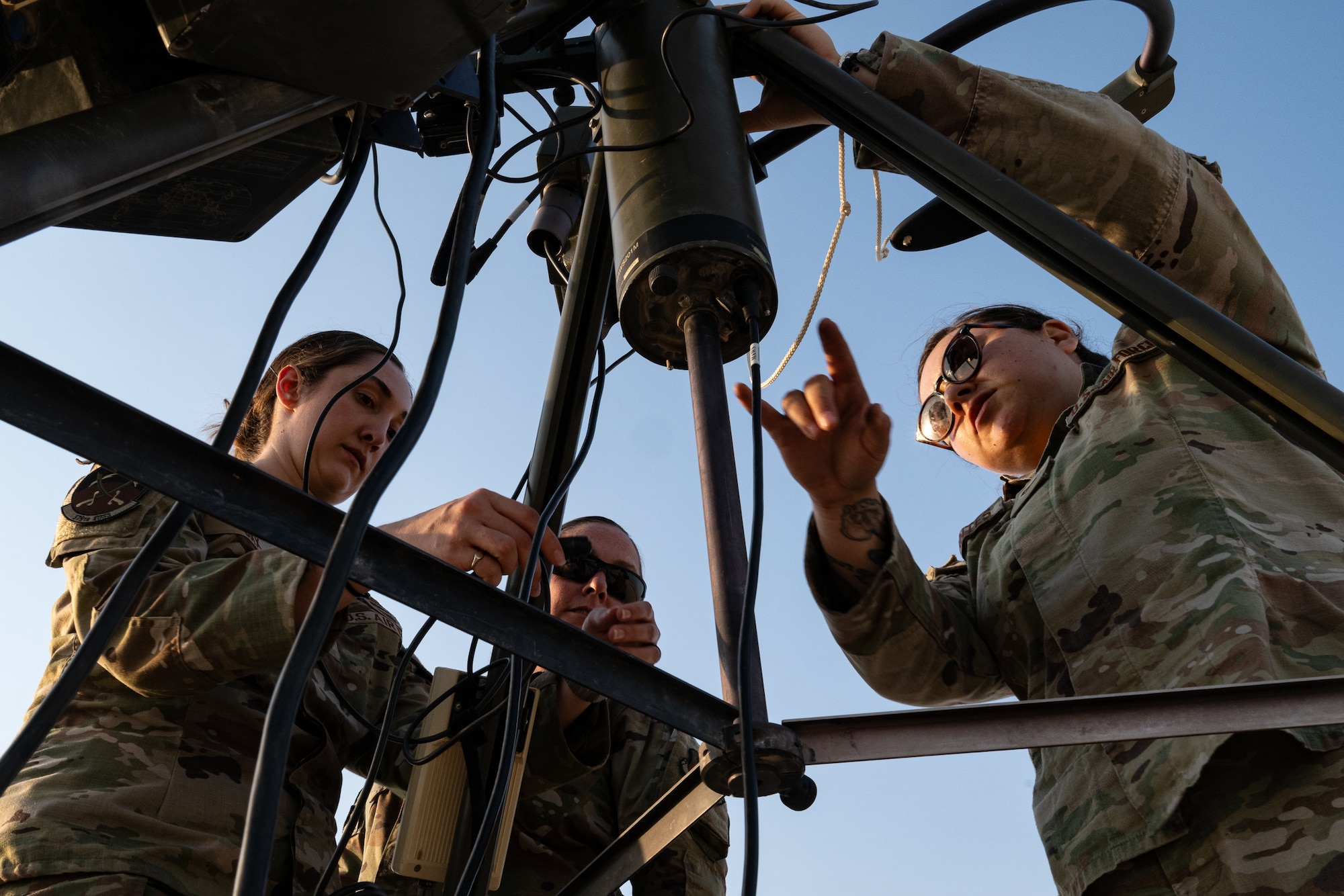 Three Airman stand around an anemometer