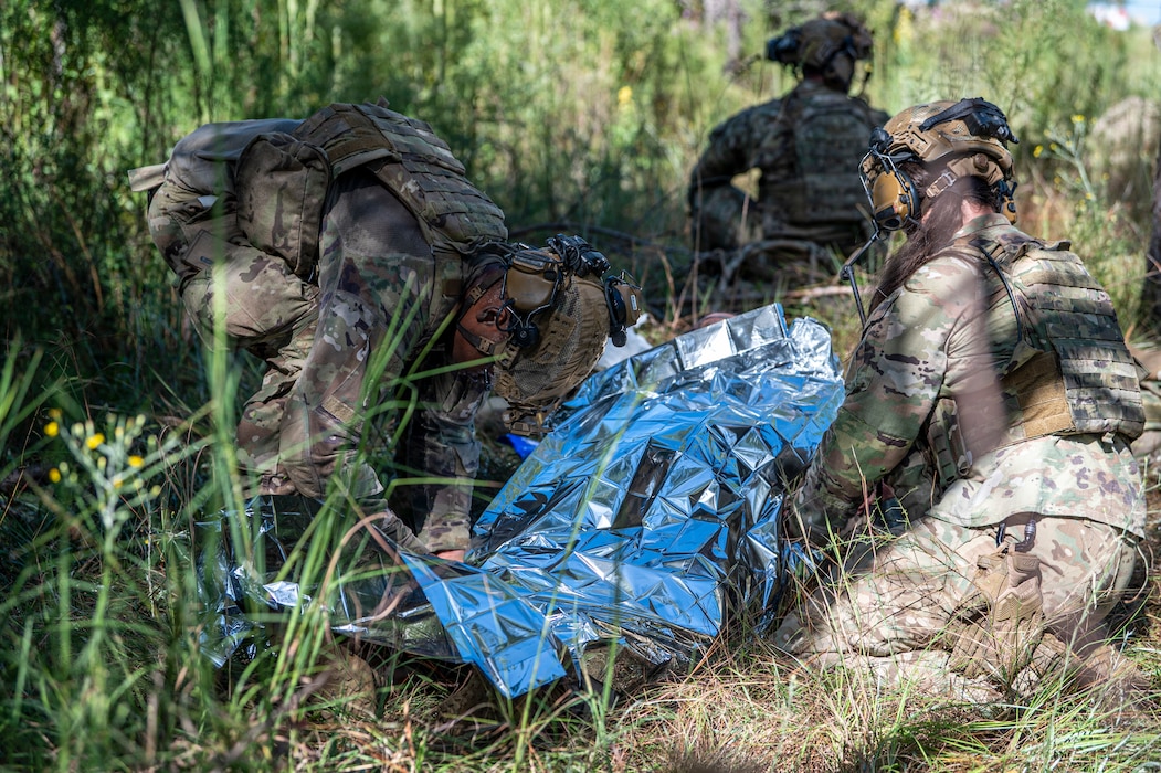 U.S. Air Force Airmen assigned to the 822nd Base Defense Squadron cover a simulated wounded Airman with an emergency blanket during Exercise IRON SAFESIDE at Moody Air Force Base, Georgia, Oct. 3, 2025. The scenario pushed Airmen to move, treat and protect —combining tactical field care with coordinated ground maneuvers under simulated combat conditions. (U.S. Air Force photo by Senior Airman Leonid Soubbotine)
