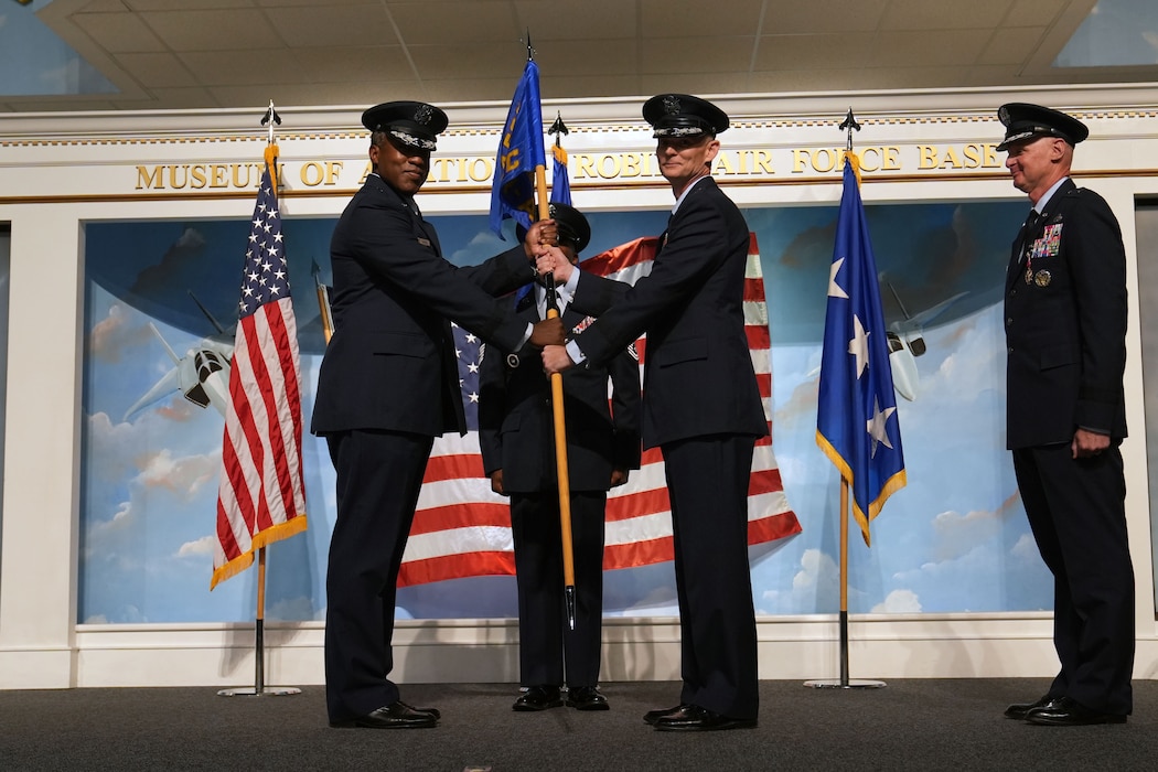 Group of men in uniform on stage pass flag from one to another