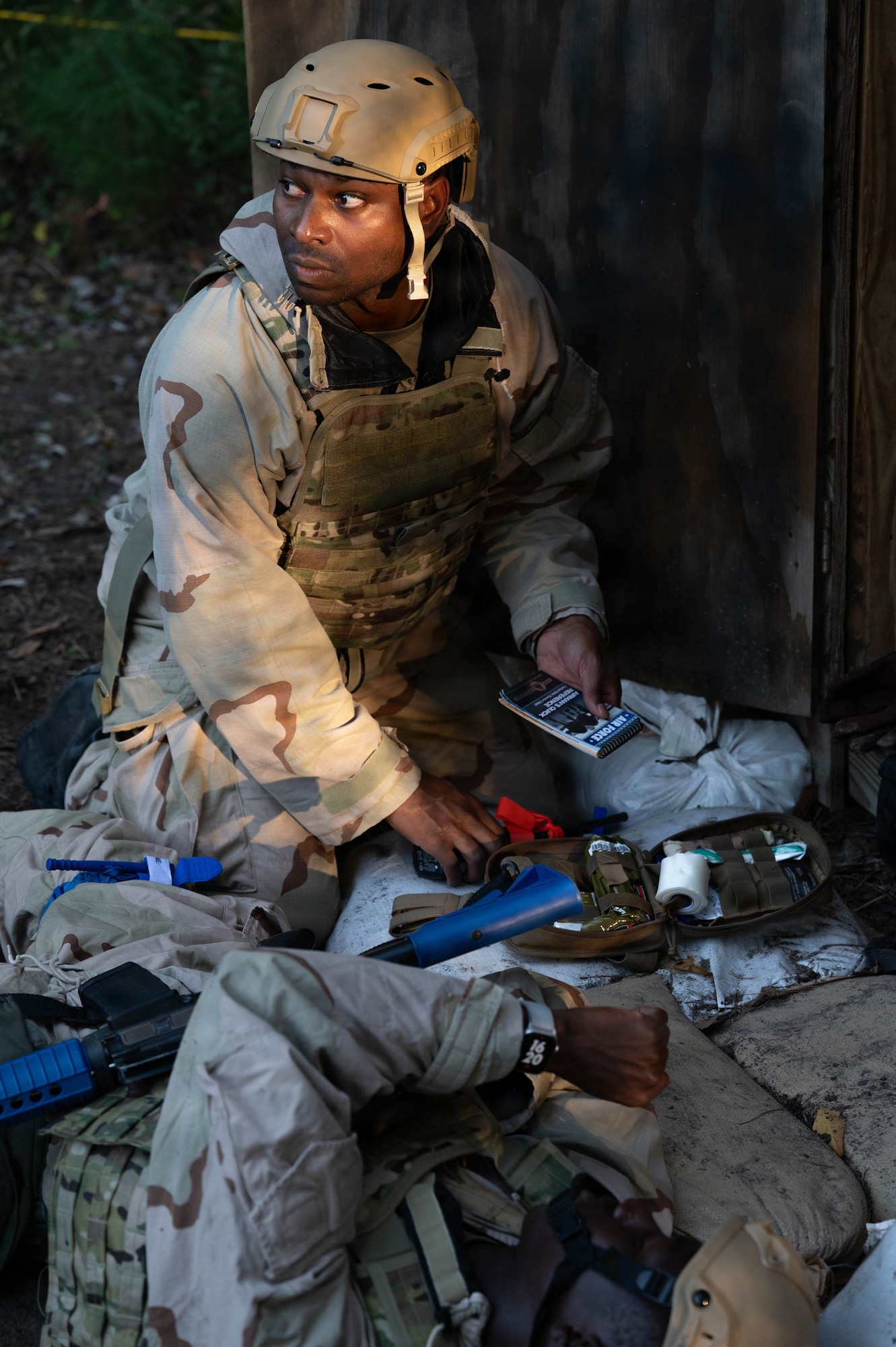 A photo of an Airman looking to the side while holding a notebook with medical gear in front of them.