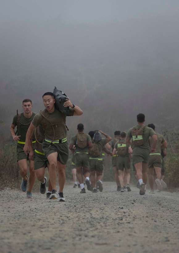 U.S Marine Corps Lieutenant Col. Brian Chong, an information warfare coordinator with I Marine Expeditionary Force Information Group, right, and Capt. David Robinson, a space plans officer with I MIG, left, conduct a unit physical training event on Marine Corps Base Camp Pendleton, California, Oct. 31, 2025. The Marines of I MIG paid tribute to their fallen comrades by running to radio tower with sandbags and ammo cans. The weight of the equipment represented the Marines' faithfulness to each other, captured in the Marine Corps motto, Semper Fidelis, meaning "Always Faithful." (U.S. Marine Corps photo by Sgt. Kristin Louise Long)