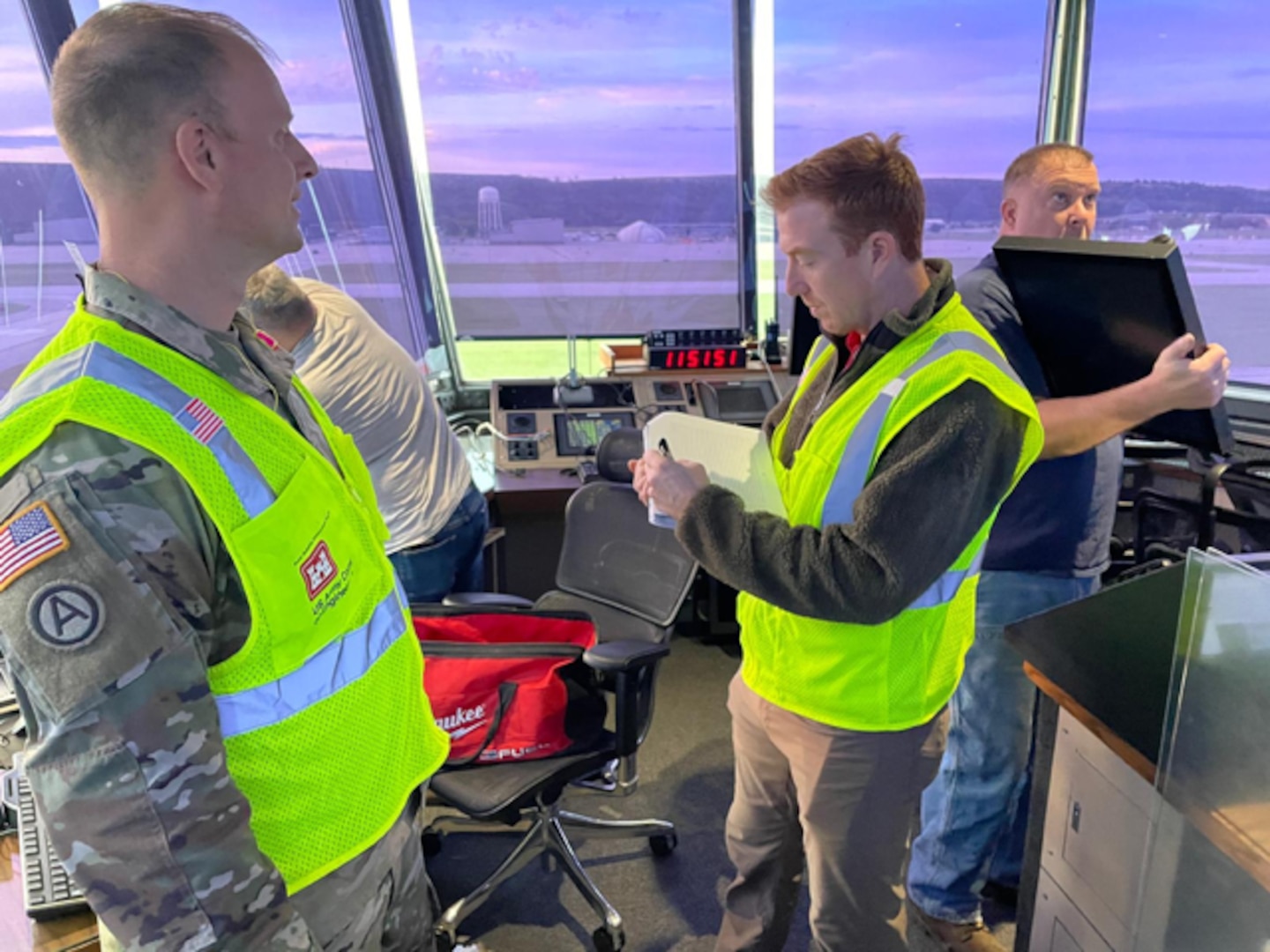 A Soldier and three other civilian men document events in an airfield tower.