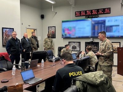 Several Army soldiers in combat uniforms are in a conference room talking with other people who are in various types of law enforcement clothing.