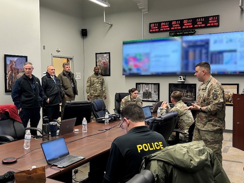 Several Army soldiers in combat uniforms are in a conference room talking with other people who are in various types of law enforcement clothing.