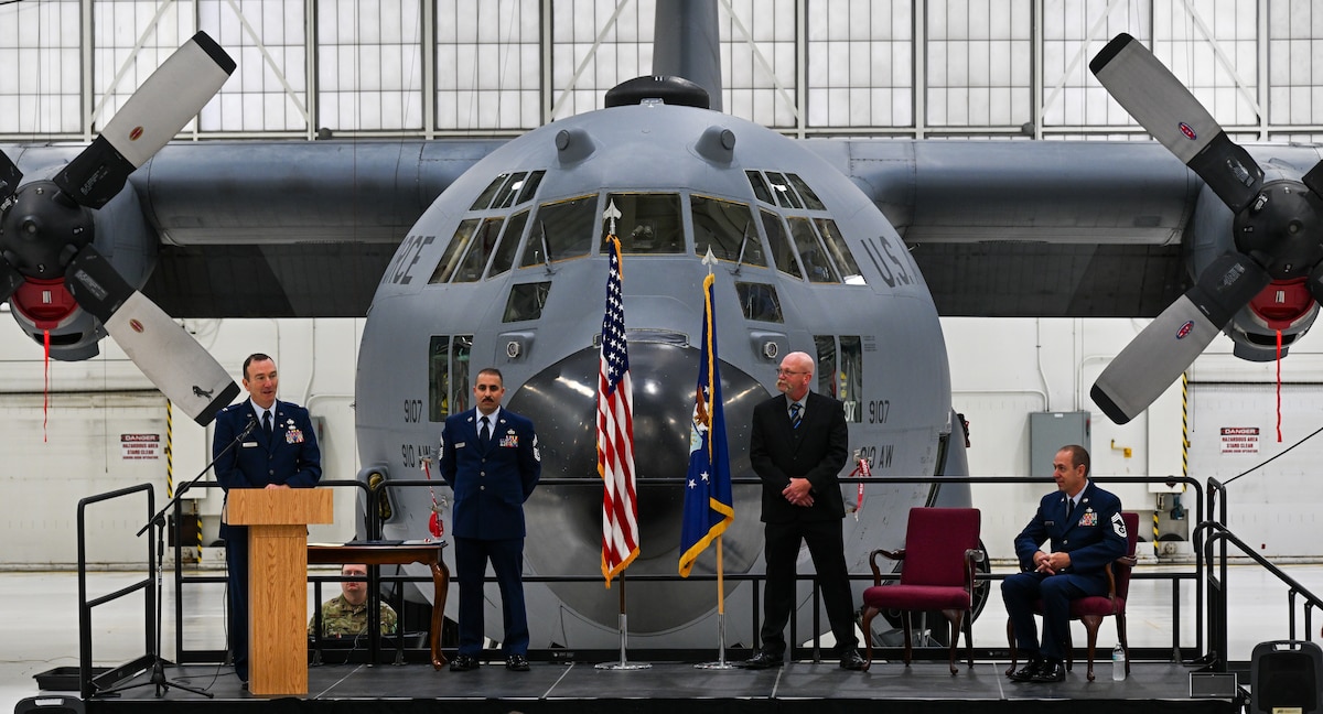 Retired Col. Raymond Otto speaks in front of a C-130H Hercules during a retirement ceremony for Chief Master Sgt. Darin J. Wesoloski, superintendent of the 910th Maintenance Squadron’s fabrication flight, seated, on Youngstown Air Reserve Station, Ohio, Nov. 15, 2025.