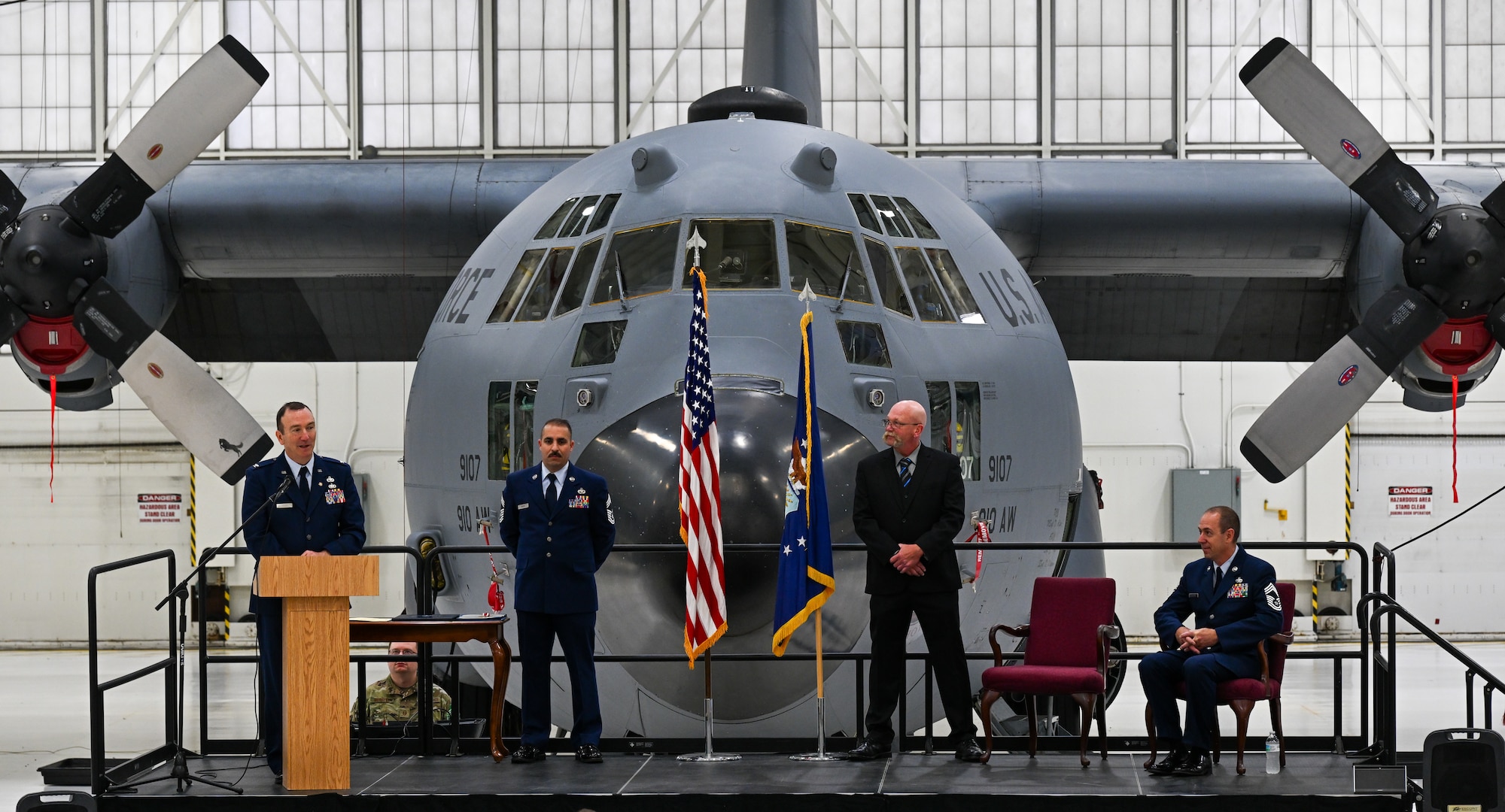 Retired Col. Raymond Otto speaks in front of a C-130H Hercules during a retirement ceremony for Chief Master Sgt. Darin J. Wesoloski, superintendent of the 910th Maintenance Squadron’s fabrication flight, seated, on Youngstown Air Reserve Station, Ohio, Nov. 15, 2025. Chief Master Sgt. Franco Russo, chief enlisted manager of the 910th MXS, inner left, and Andy Ford, a civilian in the 910th Airlift Wing’s safety office, also spoke during the ceremony. Wesoloski retired after 36 years of service in the United States Air Force. (U.S. Air Force photo by Staff Sgt. Dylan Bigelow)